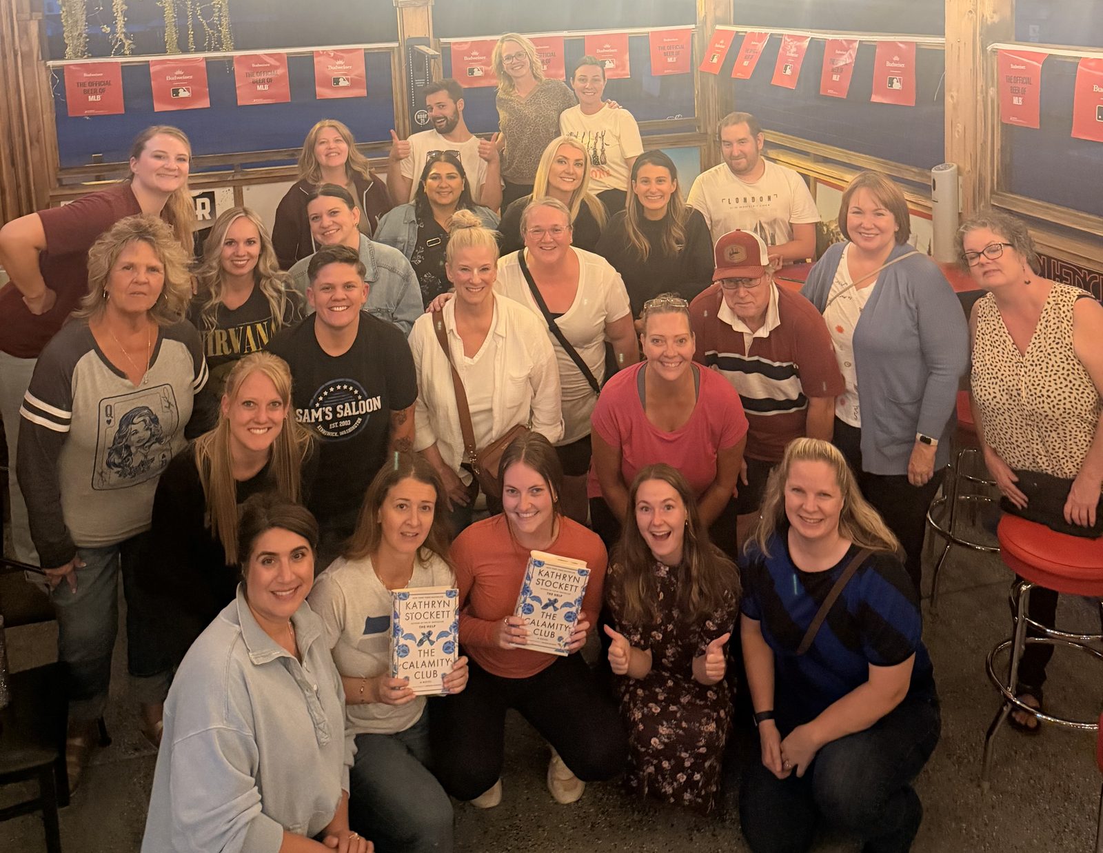 Books & Brews Book Club group photo at Sam's Saloon in Kennewick, WA, with readers holding copies of The Calamity Club by Kathryn Stockett