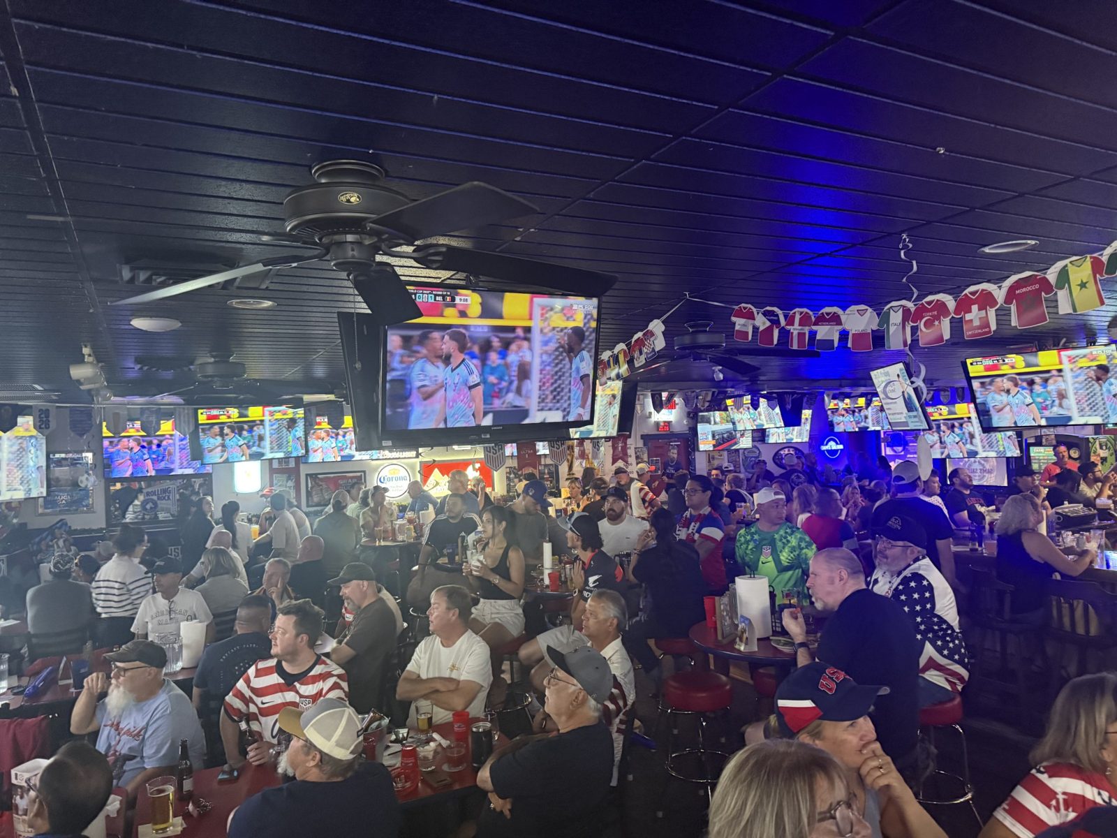 Game day crowd watching the game on the wall of TVs at Sam's Saloon